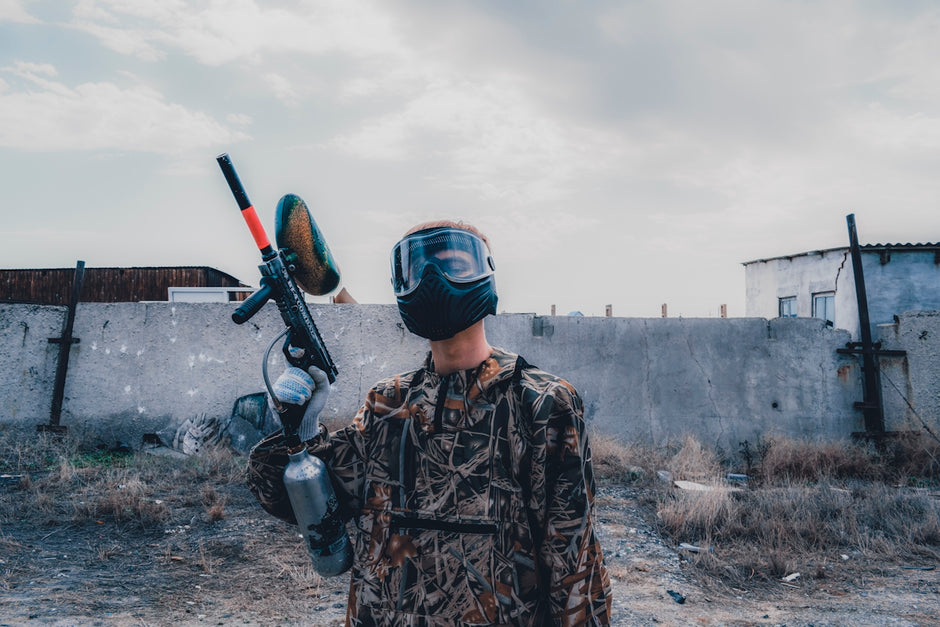 man wearing mask holding paintball gun during daytime
