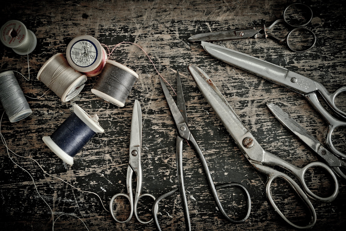 stainless steel scissors beside blue thread