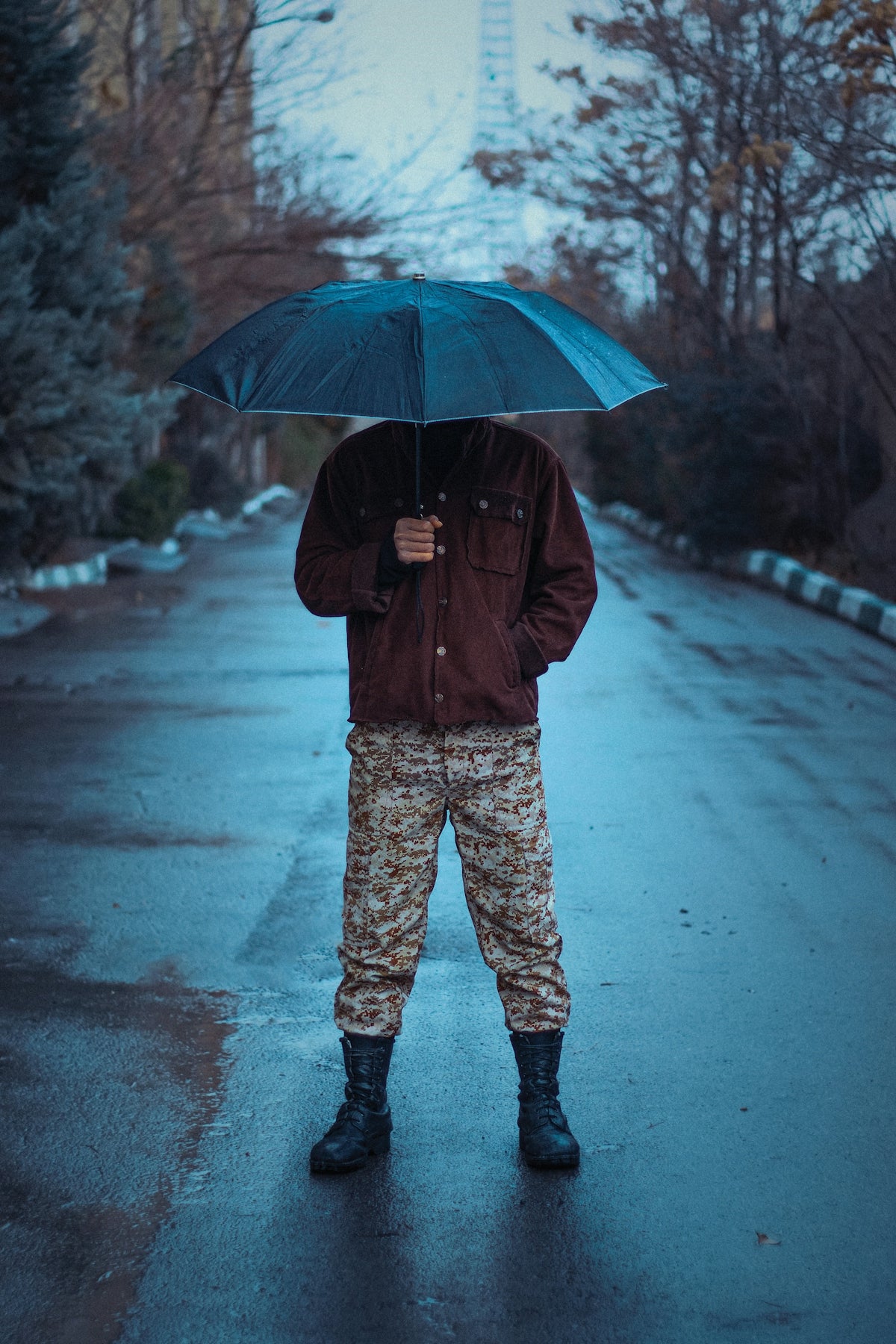 a man standing in the rain holding an umbrella