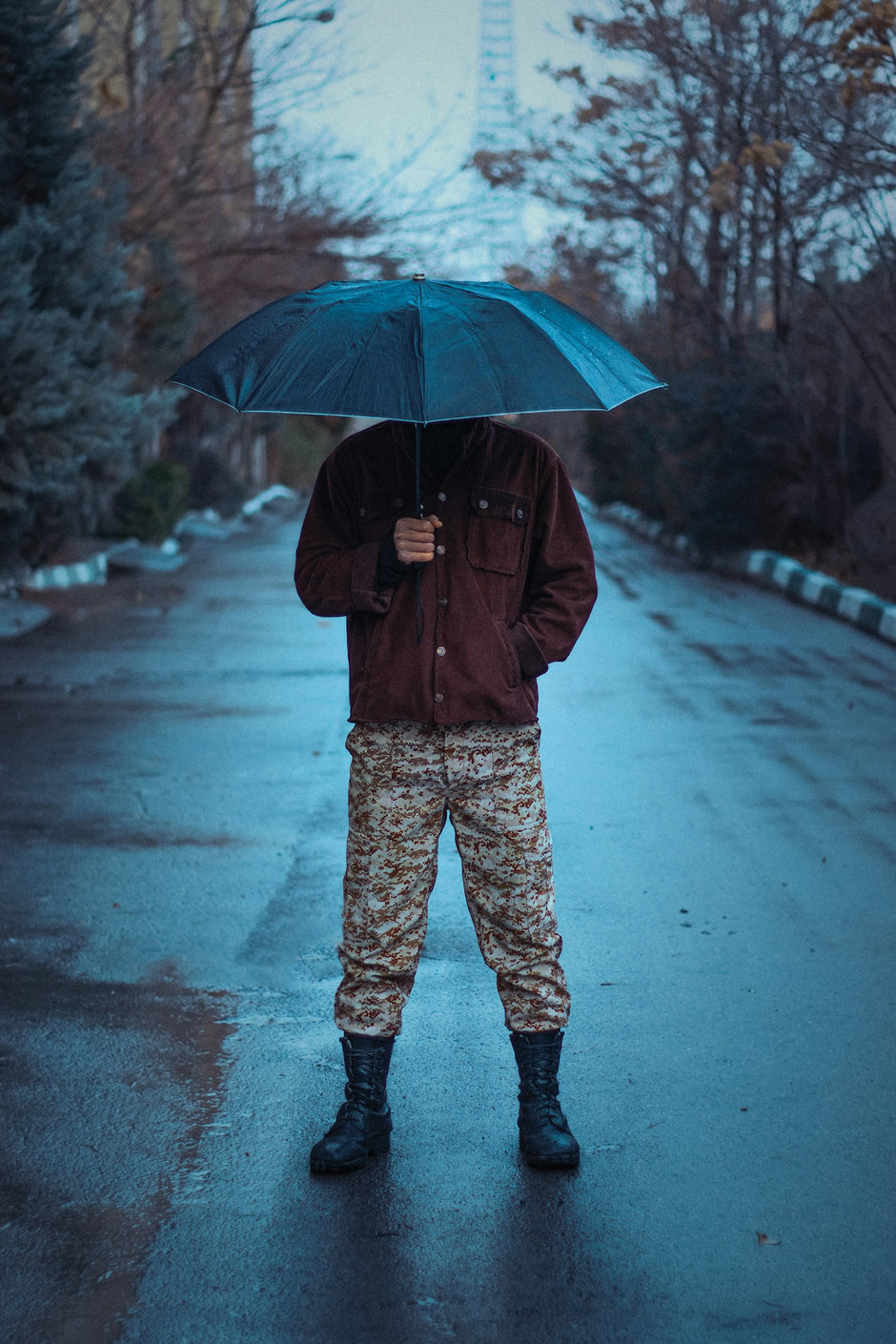 a man standing in the rain holding an umbrella