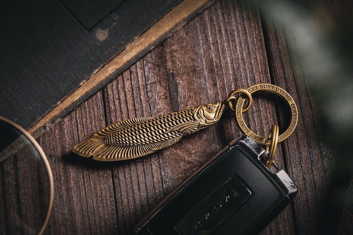 a gold keychain with a feather on it