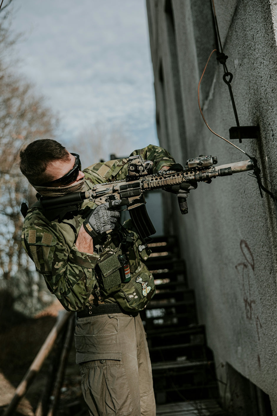 a man holding a rifle while standing next to a building
