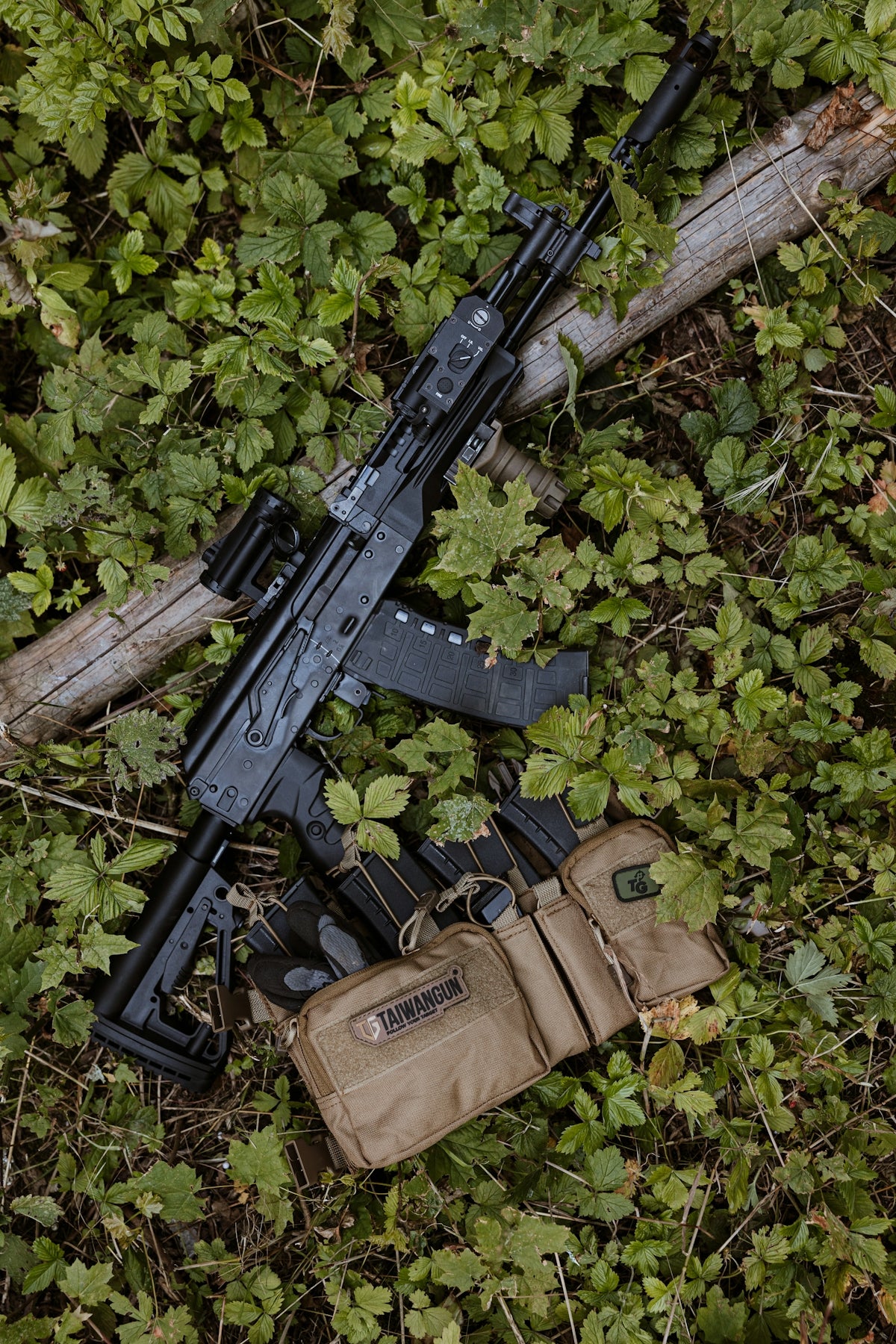 A rifle laying on the ground next to a rifle case