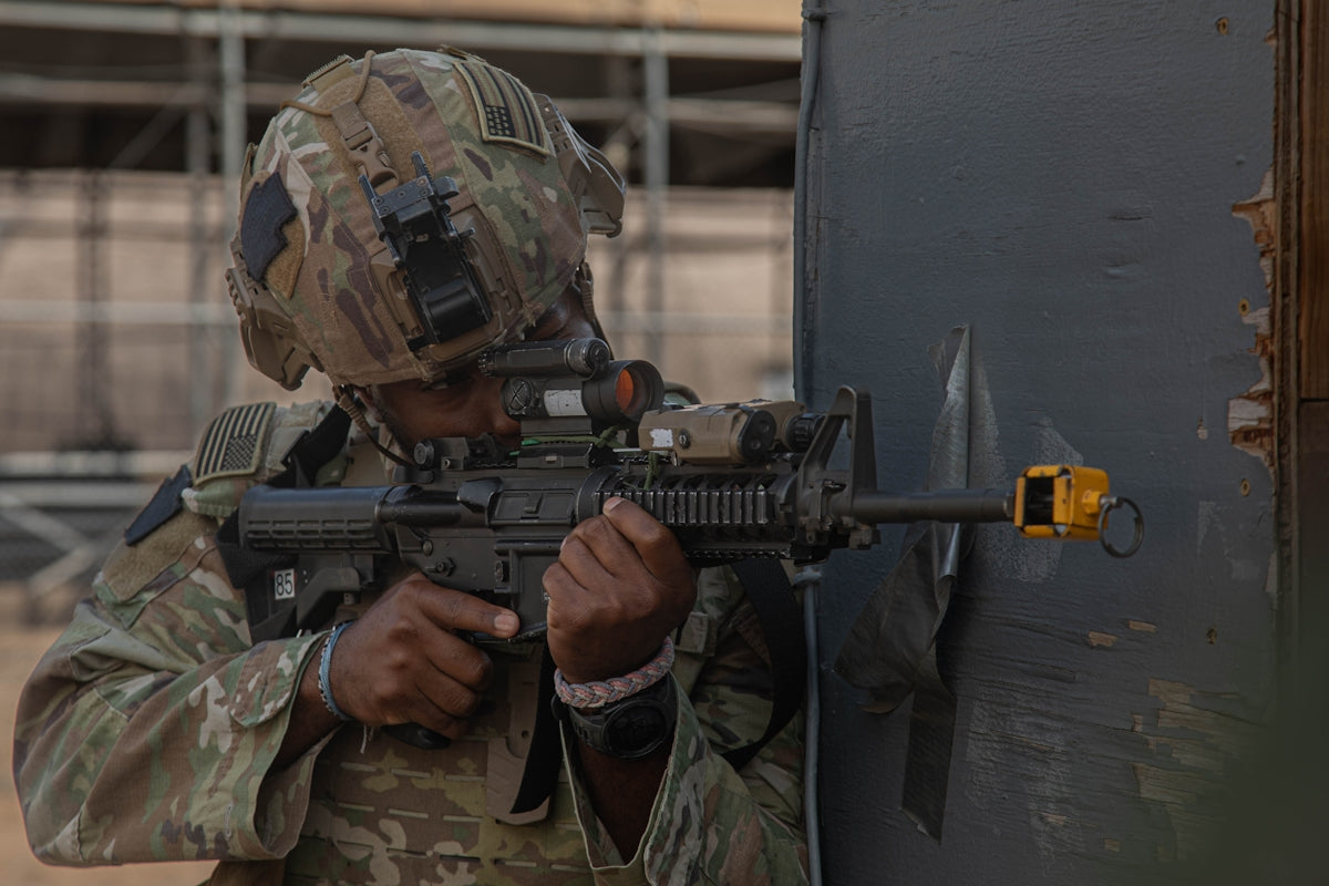 Soldier aims rifle near a damaged wall