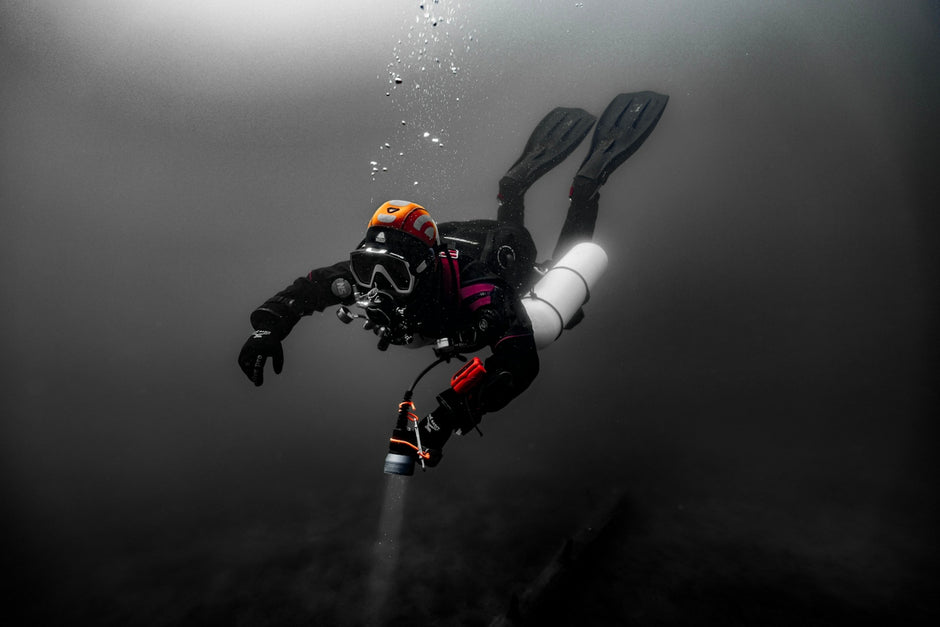 Scuba diver exploring dark underwater depths with bubbles.