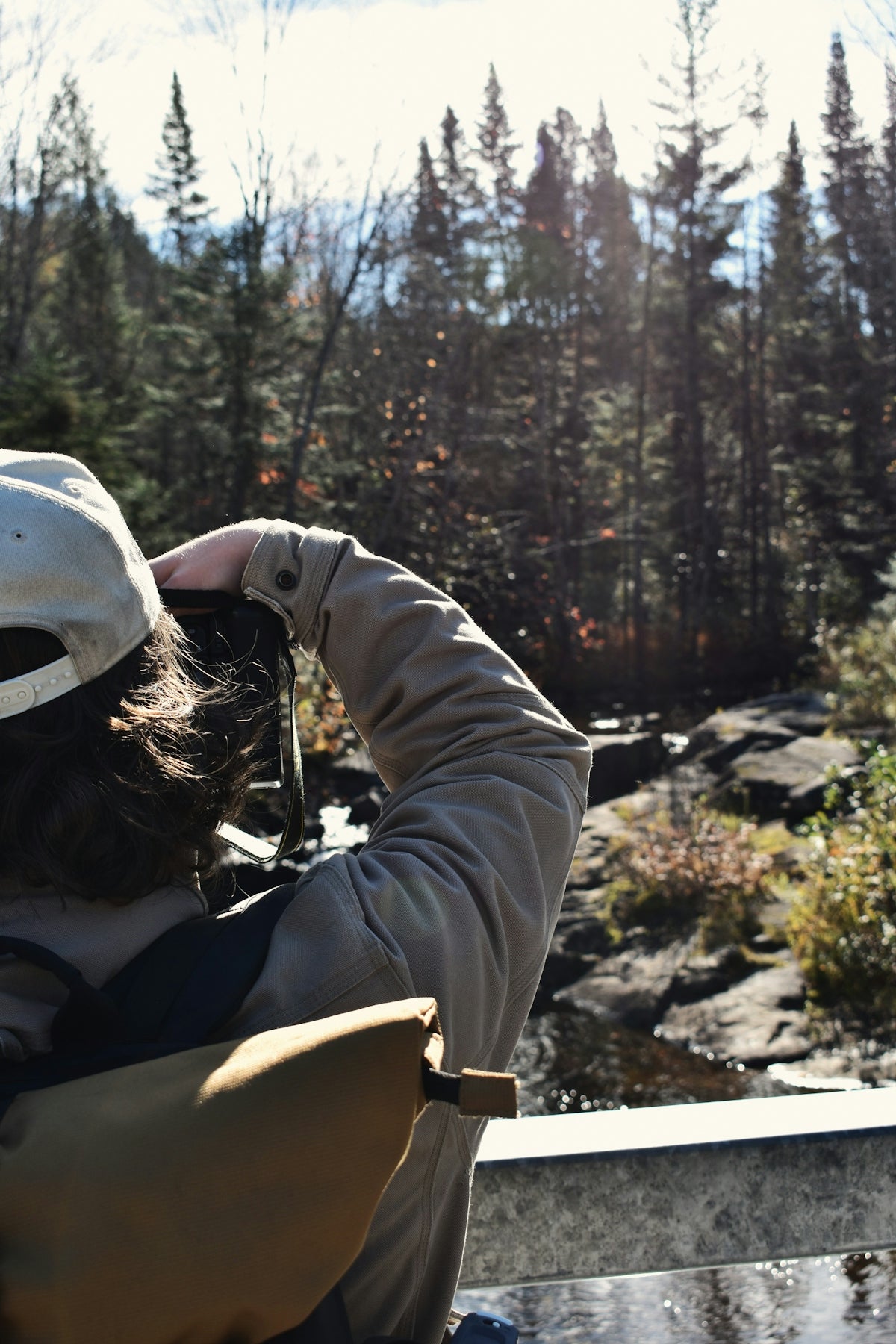 Person with binoculars looking at forest and river.
