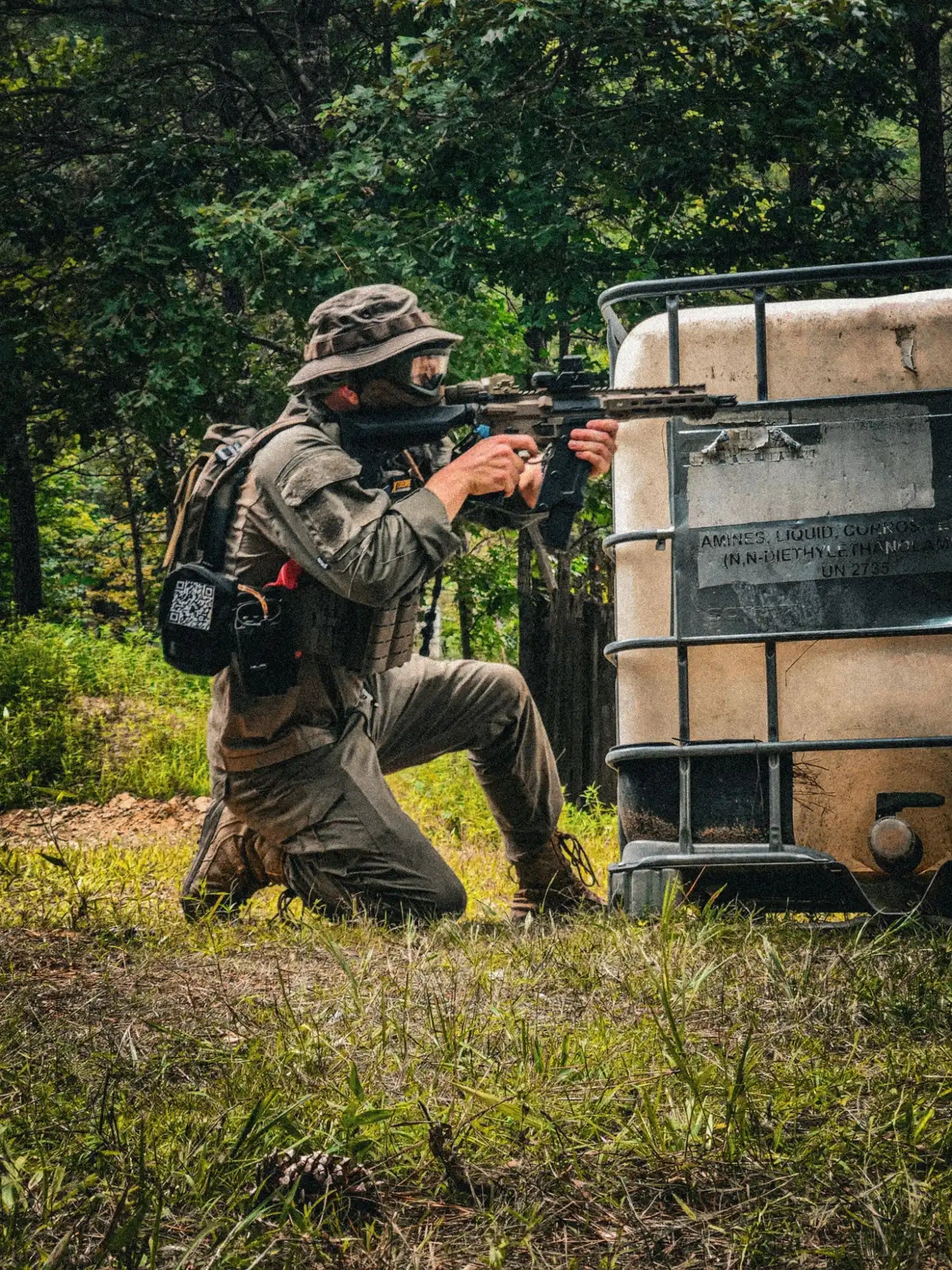 A person in tactical gear aiming a rifle.